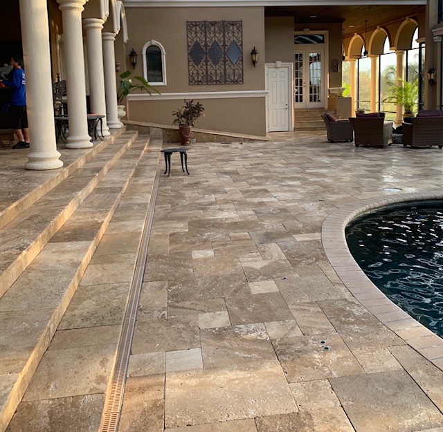 A patio with a fountain and steps leading to the pool.